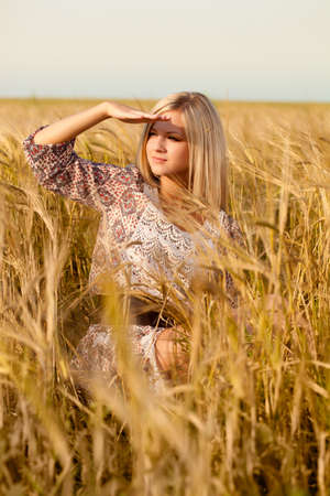 beautiful woman sitting on wheat fieldの写真素材
