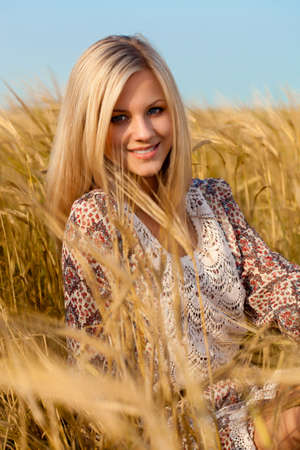 beautiful woman sitting on wheat fieldの写真素材