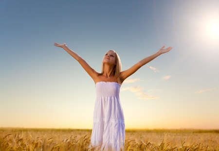 beautiful woman walking on wheat field before sunsetの写真素材