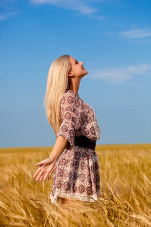 beautiful woman walking on wheat fieldの写真素材