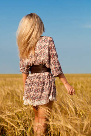 beautiful woman walking on wheat fieldの写真素材