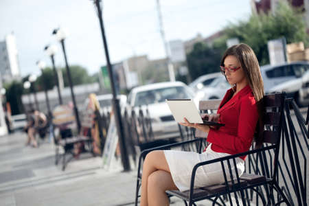 beautiful brunette businesswoman sitting on bench and work with laptopの写真素材