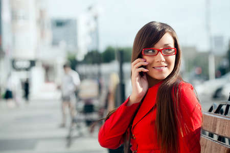 smiling businesswoman  calling by phone, wearing red glassesの写真素材