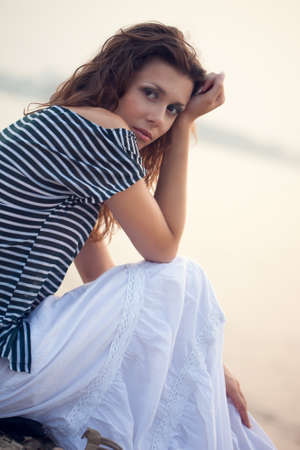 attractive  woman portrait sitting on stone beachの写真素材