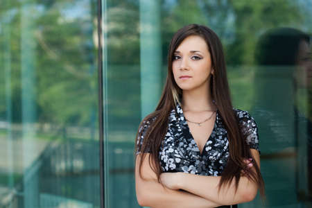 seriously brunette woman looking at camera, standing near glass wall