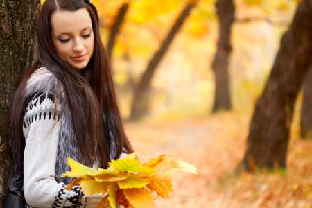 brunette woman in autmn park holding pak leavesの写真素材