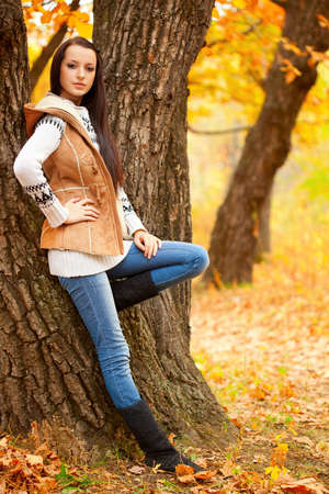 brunette woman near tree in autmn parkの写真素材