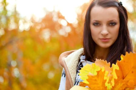 closeup brunette woman holding yellow leaves, copy spaceの写真素材