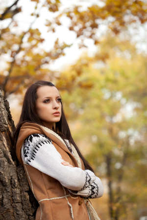 brunette woman posing near tree in autmn park, copy spaceの写真素材