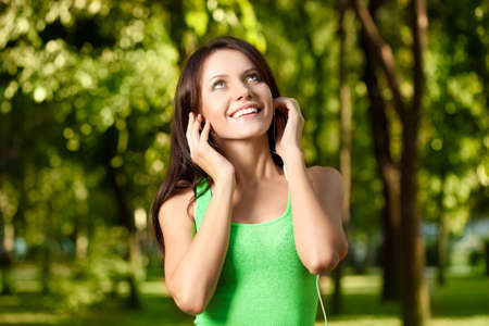 happy woman listening the music in summer parkの写真素材