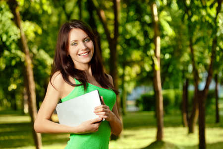 woman standing in summer park and holding laptop, copy spaceの写真素材