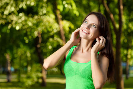 happy brunette listening music  in summer parkの写真素材