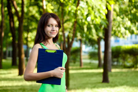 woman standing in summer park and holding tabletの写真素材