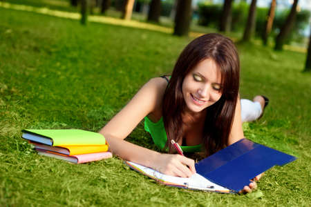 woman laying on grass and writing in parkの写真素材