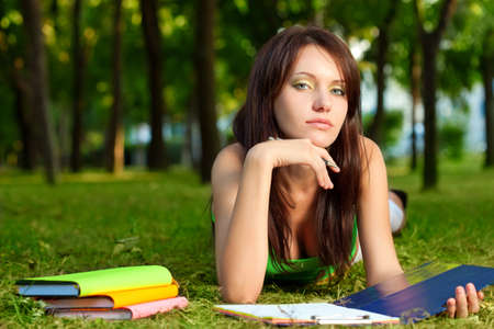 woman laying on grass in park and looking at cameraの写真素材
