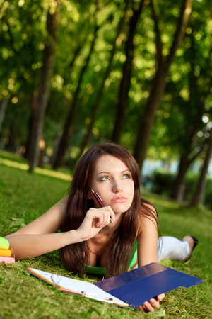 woman laying on grass and thinking in parkの写真素材