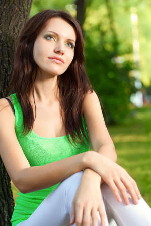 woman sitting under the tree and dreaming at summer parkの写真素材