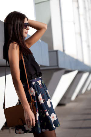 woman with leather bag near wall outdoors portraitの写真素材