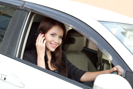 brunette woman in car calling by cell phoneの写真素材