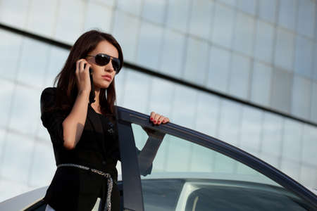 woman standing near car and calling by phoneの写真素材