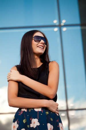brunette smiling woman wearing sunglasses over glass wallの写真素材