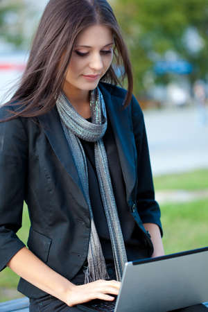 brunette woman working with laptop outdoorsの写真素材