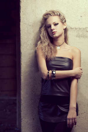 blond woman near column looking at camera wearing tunic. Fashion photoの写真素材