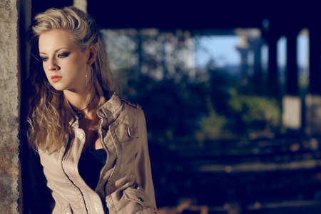 portrait blond woman wearing leather beige jacket inside ruins. Fashion photoの写真素材