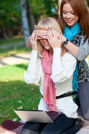 two sisters with laptop playing  in the summer parkの写真素材