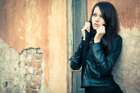 brunette woman standing near wall and holding her collarの写真素材