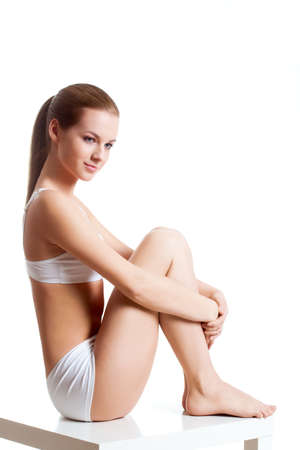 beautiful blonde woman wearing white underwear sitting on tableの写真素材