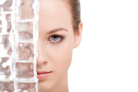 beautiful woman face near ice cubes over white background. Look at cameraの写真素材