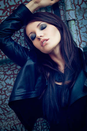 brunette woman with closed eyes near cracked wall. Specially toned fashion photoの写真素材