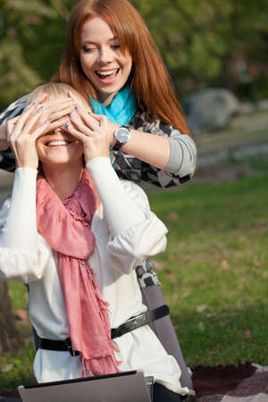 two sisters with laptop having fun in the summer parkの写真素材