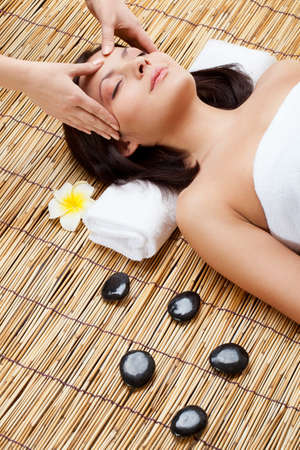 massage in spa salon, woman laying on bamboo matの写真素材