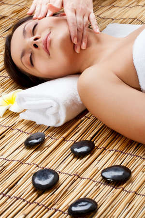 brunette woman in spa salon. Massage of neck and faceの写真素材