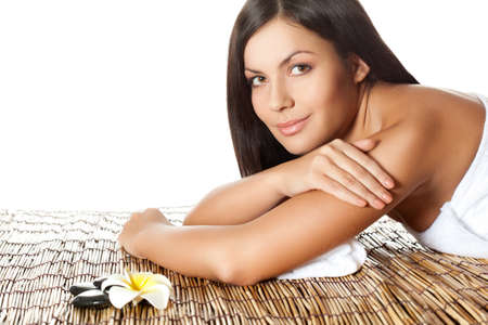 woman laying on bamboo mat in spa salon, looking at cameraの写真素材