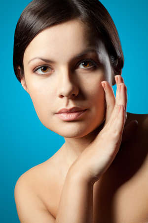 woman closeup face with hands over turquoise backgroundの写真素材