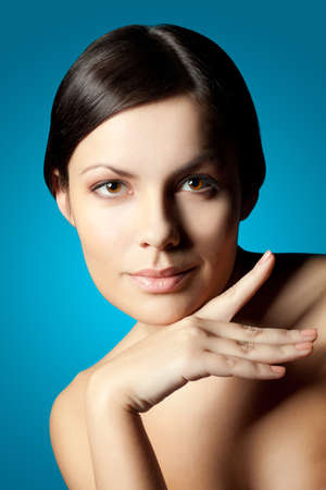 smiling woman closeup face with hands over blue backgroundの写真素材