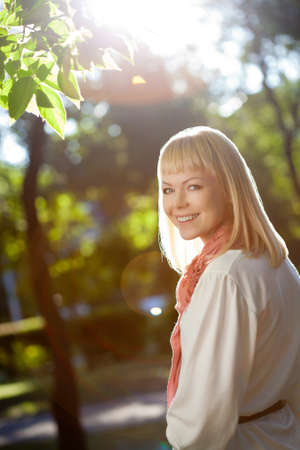 beautiful blond woman walking in the summer park, backlight flaresの写真素材