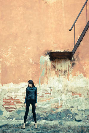 brunette woman wearing leather jacket on ruins near stairwayの写真素材
