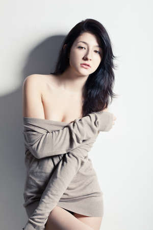 brunette woman posing at studio near wall, looking at cameraの写真素材