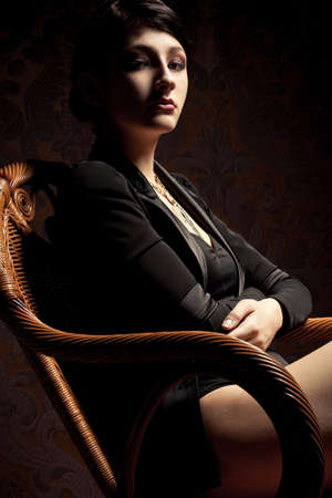 brunette sexy woman sitting in wood chair, vertical portraitの写真素材