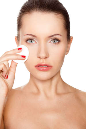 brunette woman cleaning her face with cotton spongeの写真素材
