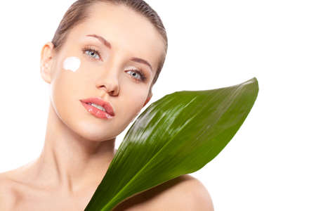 beautitful woman closeup face portrait with green leaf and cream on faceの写真素材