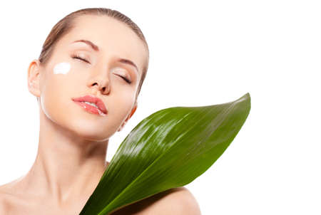 beautitful woman  face portrait with green leaf and cream on face, closed eyesの写真素材