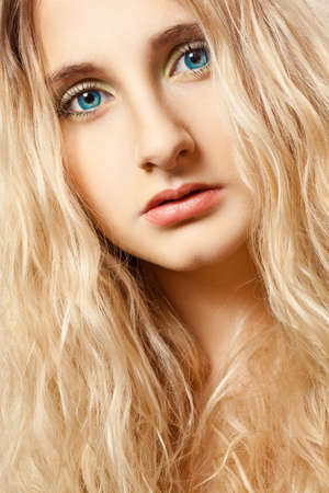 woman portrait with bright blue eyes and curly hairs, looking to the cameraの写真素材