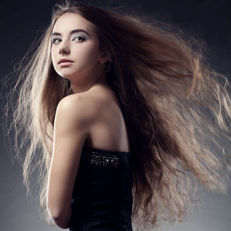 brunette woman with long flying  hair looks backの写真素材
