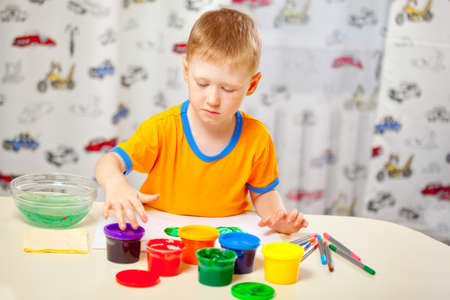 Boy finger paints on paper at his roomの写真素材