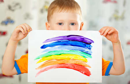 boy holding paper with painted  rainbowの写真素材